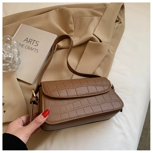 Close-up of brown crocodile texture leather and golden metal hardware on a shoulder bag