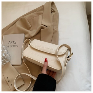 Detail of creamy white faux leather shoulder bag with crocodile pattern texture