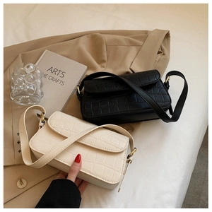 Close-up of black and cream faux leather bags with crocodile pattern and gold buckles