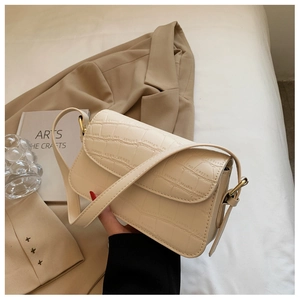 Close-up of beige crocodile pattern texture and golden hardware on a shoulder bag