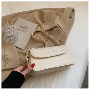 Close-up of cream crocodile pattern shoulder bag with gold hardware buckle detail