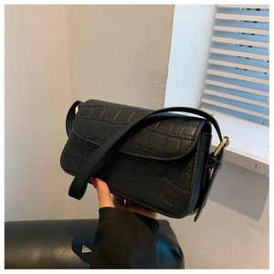 Detail view of black crocodile pattern faux leather bag with elegant gold buckle and strap