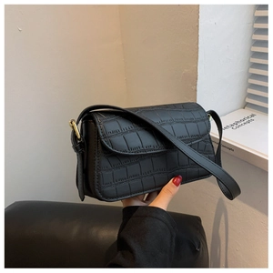 Close-up of black crocodile pattern faux leather shoulder bag with gold buckle detail