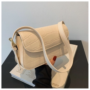 Close-up detail of ivory crocodile pattern shoulder bag with golden metal hardware buckle