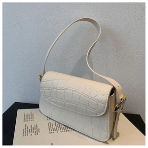 Detail of cream crocodile embossed flap bag with gold hardware and adjustable strap