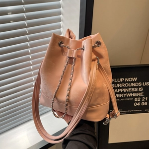 Pink drawstring bucket bag with silver chain and mixed leather textures shown in lifestyle setting