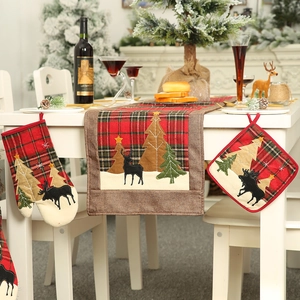 Christmas table set with red plaid oven mitts, placemat, and festive table runner