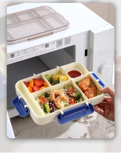 Detail showing a four-compartment lunch box with blue side locks inside a microwave