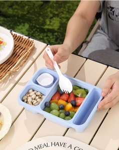 Detail view of light blue partitioned lunch box filled with fruit and a white spork tool