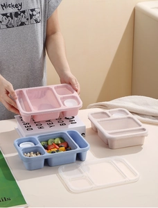 Close-up of three-compartment plastic bento lunch boxes with transparent lids in pastels