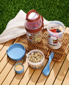 Dual-layer plastic yogurt cup set with sauce container and fork on a picnic table