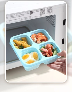 Detailed view of 4-compartment blue bento box with food inside a microwave oven