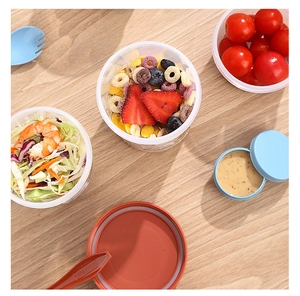 Top view of portable plastic salad cup with BPA free fork on light wood background