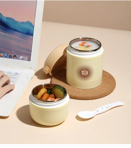 Close-up of insulated cream stainless steel soup cups with lids and spoon on wooden coaster