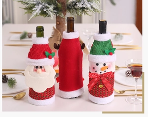 Three 3D cartoon Christmas wine bottle covers with Santa and Snowman on a festive table