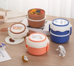 Detail of multi-layer round bento box with cartoon lids and secure side buckles on a desk