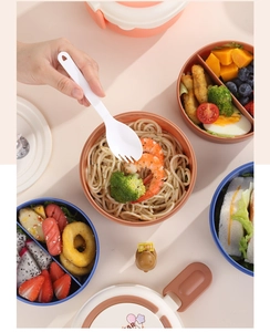 Detail view of multi-layer bento box with divided compartments for pasta and fresh fruits