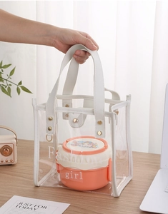 Transparent PVC tote bag with white leather handle holding a stacked orange bento box inside