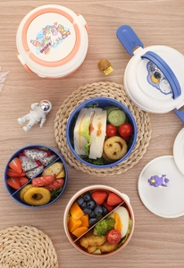 Detail of round bento box with stackable layers, cute cartoon patterns and side latches