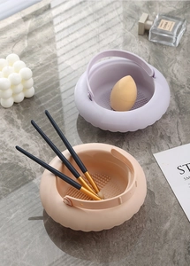 Silicone makeup brush cleaning bowls with textured bottoms and handles in soft pastel tones