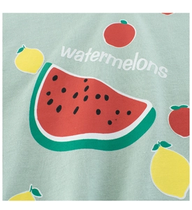 Dettaglio del tessuto in cotone verde menta con stampe di anguria e frutta sulla maglia