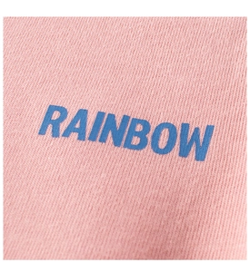 Close-up of pink knit fabric detail with blue RAINBOW text printing for girls' t-shirt