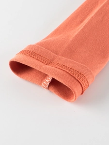 Nahaufnahme von orangem Baumwollärmel mit sauberer Naht an diesem Kinder-T-Shirt