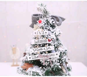 Close-up of wooden Christmas tree hanging sign with red star, bird and plaid bow details