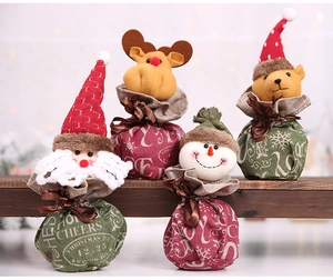 Linen Christmas gift bags featuring Santa, elk, and snowman characters on a wooden shelf