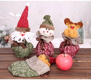Detail of burlap Christmas gift bags featuring cartoon Santa and snowman designs