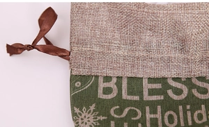 Close-up of burlap Christmas gift bag with silk ribbon drawstring and holiday printing