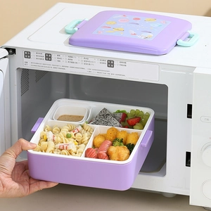 Boîte bento violette thème espace avec quatre compartiments dans un micro-ondes