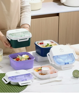 Close-up of dual-layer lunch box lid with folding utensil storage and a clear window