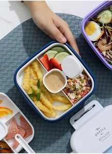Detail of multi-compartment lunch box with separate sections for salad and snacks