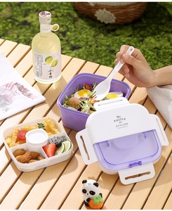 Detail view of purple double-layer bento box with dividers and cutlery on a wooden table
