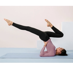 Detalle de mallas de yoga de talle alto en postura de estiramiento sobre esterilla