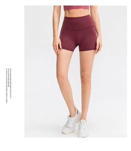 Detail of high-waisted burgundy yoga shorts showing elastic waistband and seamless stitching