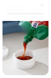 White plastic dipping sauce cup with lid being filled with tomato ketchup close-up
