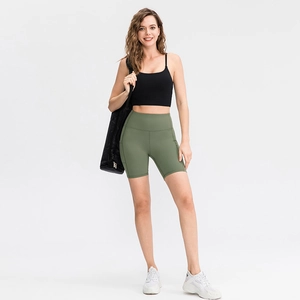 Women's pocket yoga shorts in olive green paired with a black thin strap sports tank top