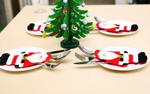 Dettaglio di portaposate a tema Babbo Natale in feltro rosso su piatti di ceramica bianca