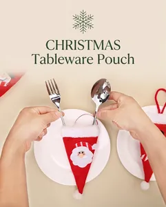Hands placing cutlery into mini Santa hat holders for festive Christmas table decor