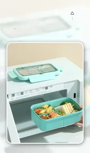 Detail of mint green bento box with 3 compartments being taken out of a microwave