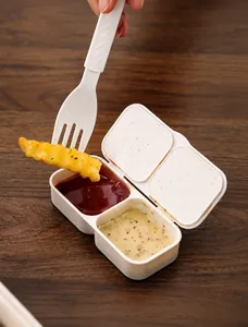 Détail du compartiment à sauce blanc cassé avec couvercle et une fourchette trempée