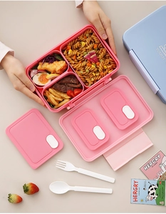 Three-compartment pink bento box with blue lid and utensils showing meal prep storage