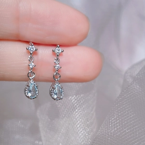 Light blue teardrop earrings in S925 silver with sparkling zircon held by fingers