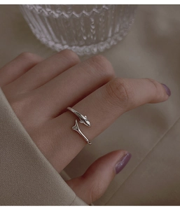 Close-up of S925 silver dolphin-shaped open ring worn on finger with soft warm lighting