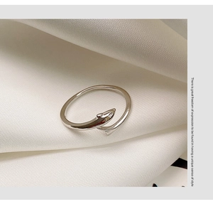 Close-up of a silver shark-shaped open ring on white pleated silk fabric