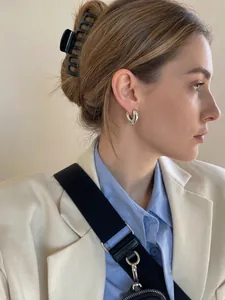 Close-up of a silver heart-shaped hoop earring worn by a model in a minimal setting
