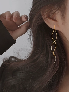 Close-up of elegant gold spiral wave drop earrings worn to enhance facial profile