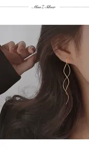 Elegant gold wave-shaped spiral long drop earrings worn by a model to show fluid motion